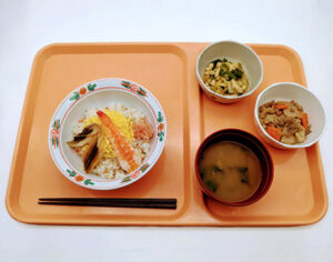 介護施設の食事トレー。主菜、副菜、汁物、箸が配置された配膳の様子。